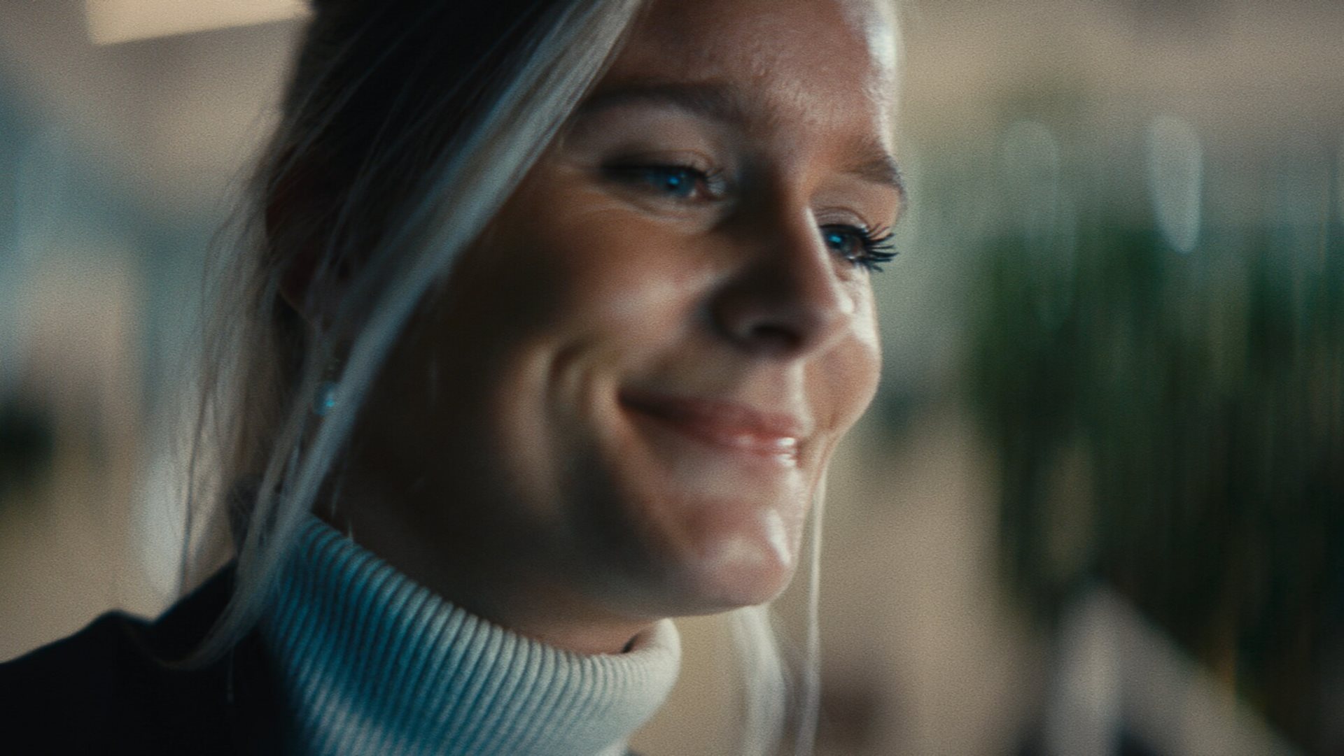 A woman with blonde hair smiles while looking away from the camera. A woman with blonde hair smiles while looking away from the camera.