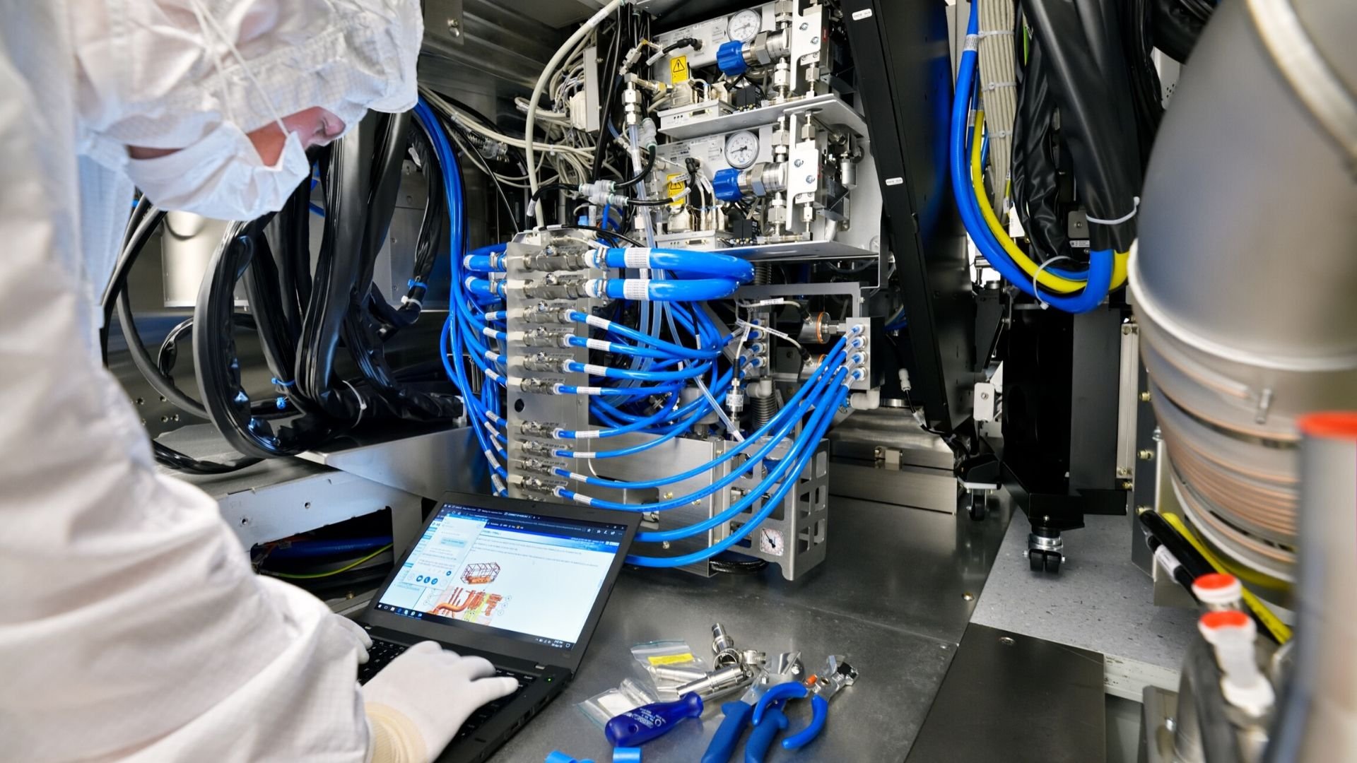 An ASML EUV customer support engineer troubleshoots a machine inside a cleanroom An ASML EUV customer support engineer troubleshoots a machine inside a cleanroom