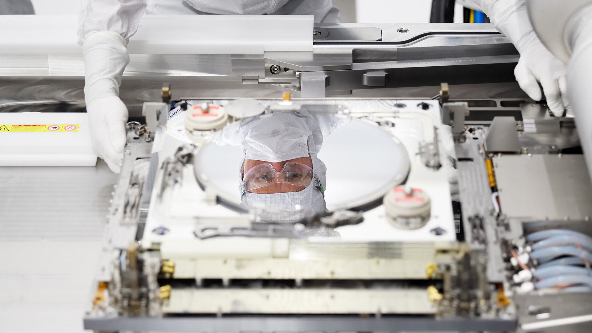 Reflection of engineer in protective clothing looking at silicon wafer Reflection of engineer in protective clothing looking at silicon wafer