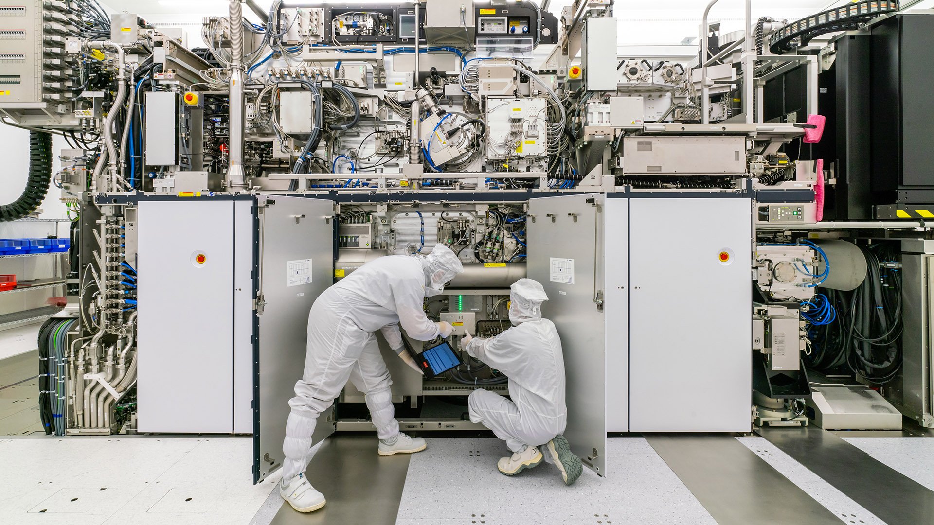 Two people in cleanroom suits working on ASML lithography machine Two people in cleanroom suits working on ASML lithography machine