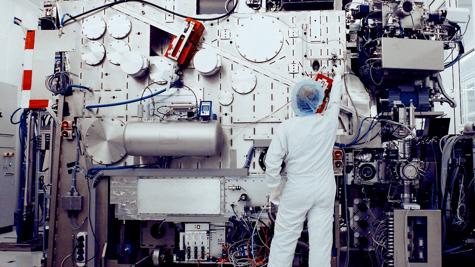 A cleanroom engineer adjusts a knob on a prototype ASML EUV system. A cleanroom engineer adjusts a knob on a prototype ASML EUV system.