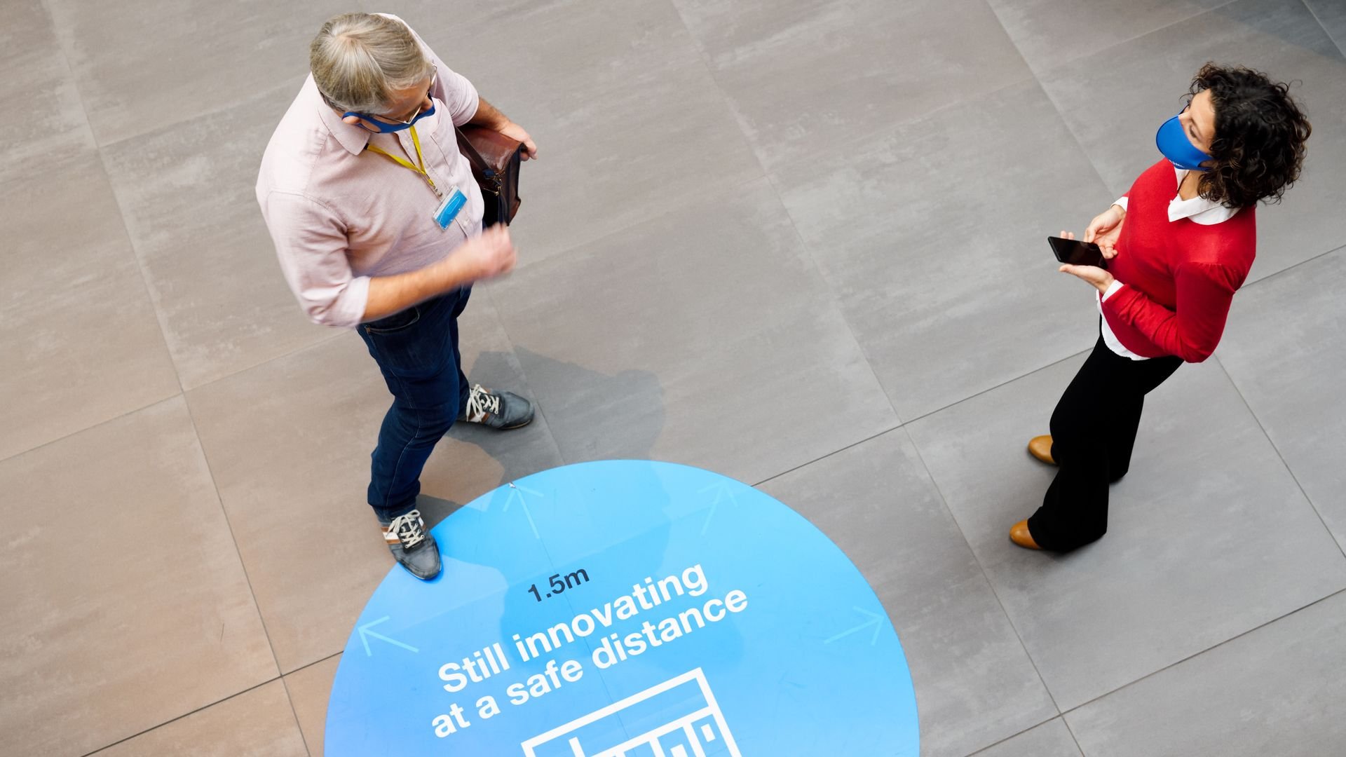 man and woman talking standing over sign for COVID-19 social distancing man and woman talking standing over sign for COVID-19 social distancing