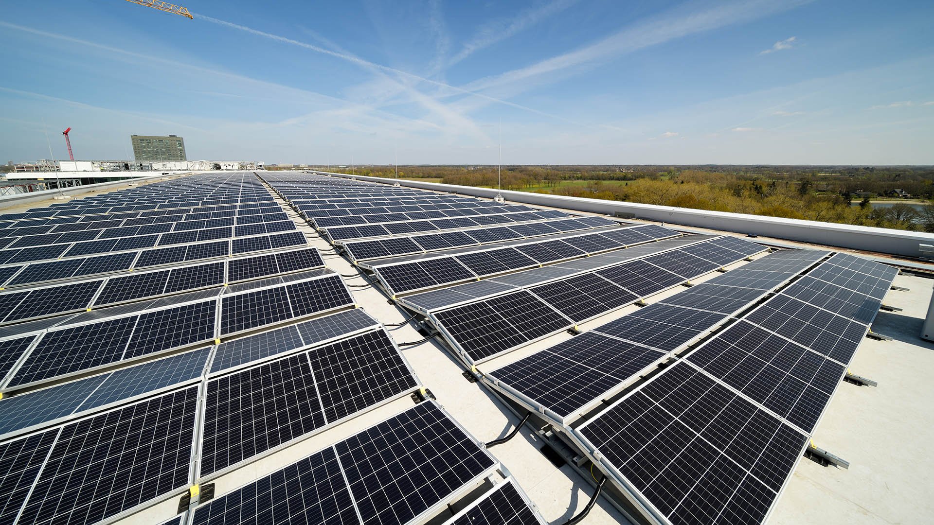 Rows of solar panels on a building roof under a blue sky Rows of solar panels on a building roof under a blue sky