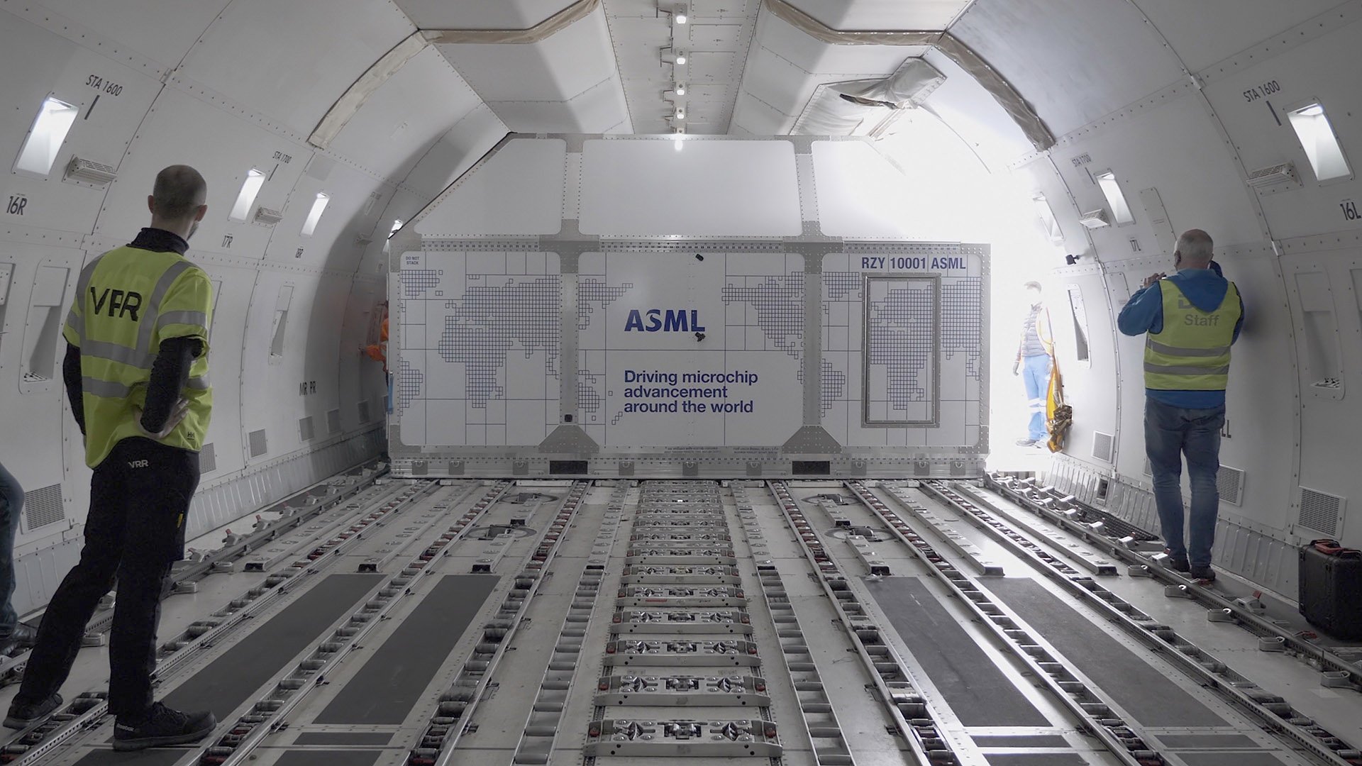 Three people unloading a lithography machine from an airplane Three people unloading a lithography machine from an airplane