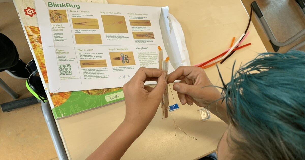Student assembling BlinkBug STEM challenge with instructions