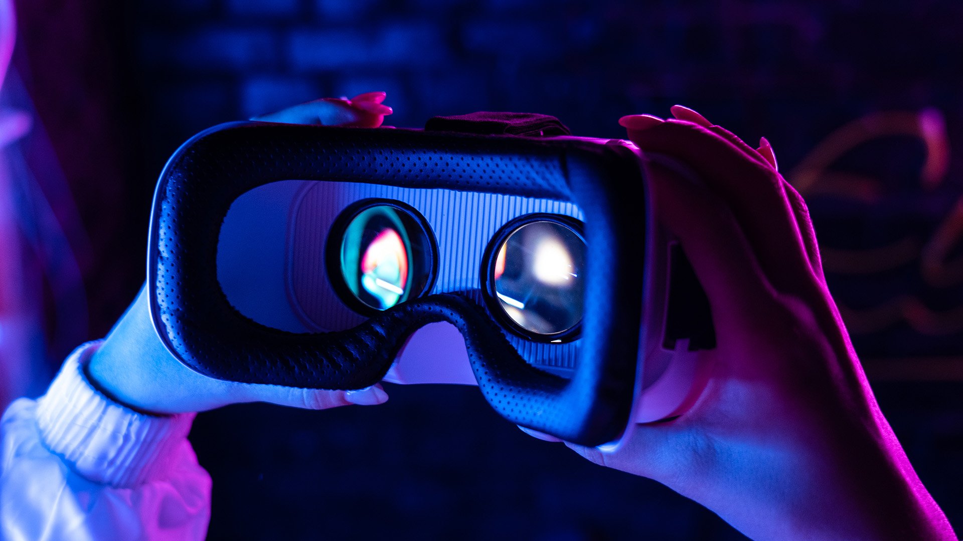 Hands holding a virtual reality face mask in low light Hands holding a virtual reality face mask in low light